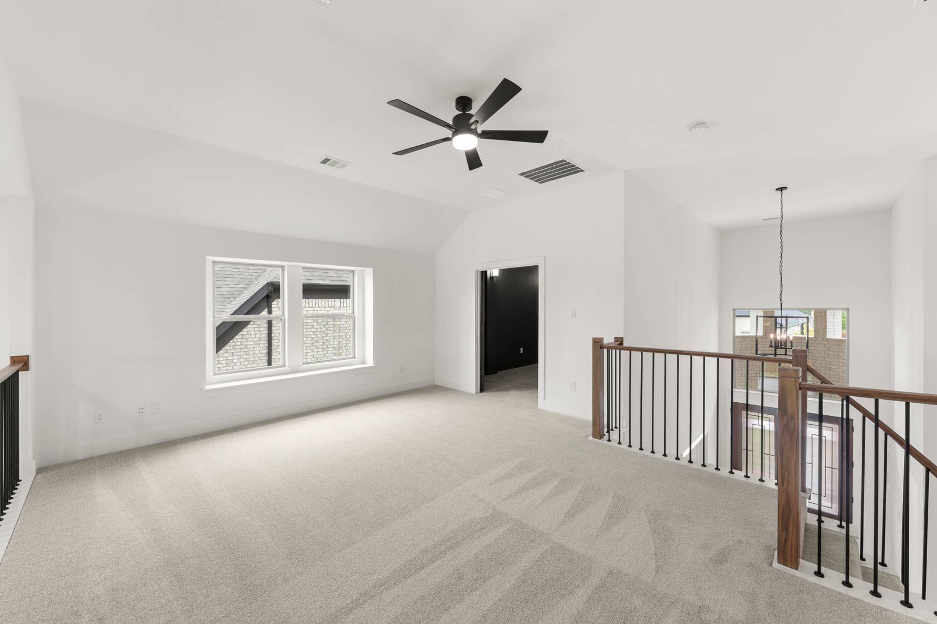Spacious interior loft with carpet, ceiling fan, and modern railing.