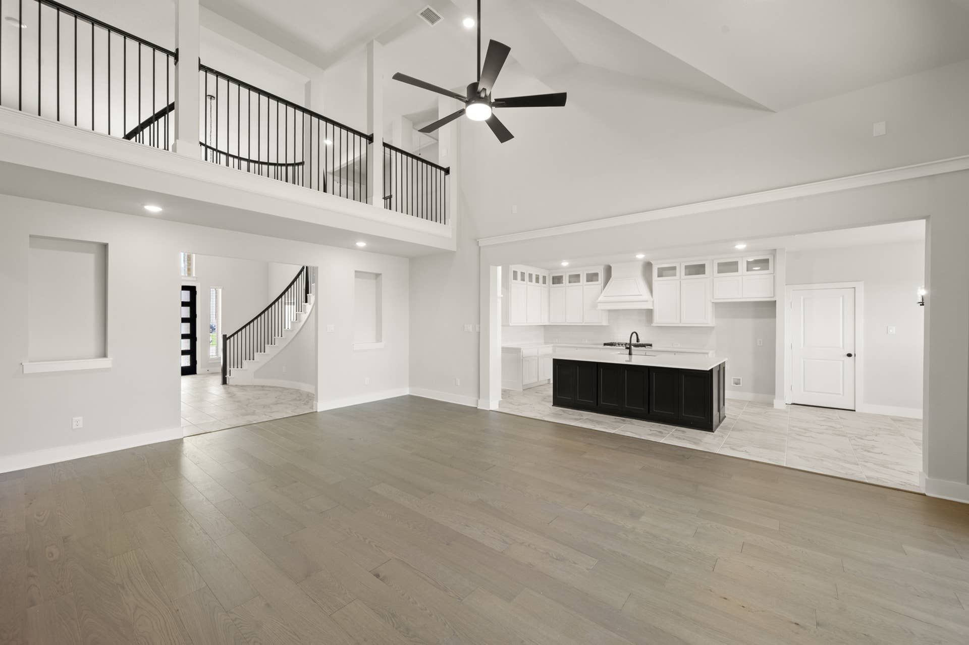 Spacious modern living room with high ceilings, open kitchen, and elegant staircase.