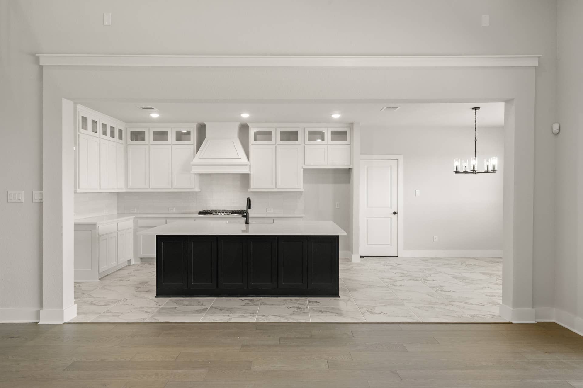 Modern kitchen with white cabinetry, black island, and tiled flooring.