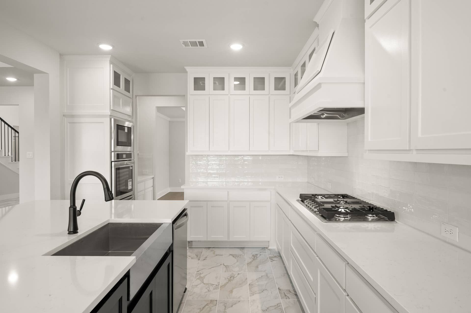 Modern kitchen with white cabinetry, marble flooring, and stainless steel appliances.