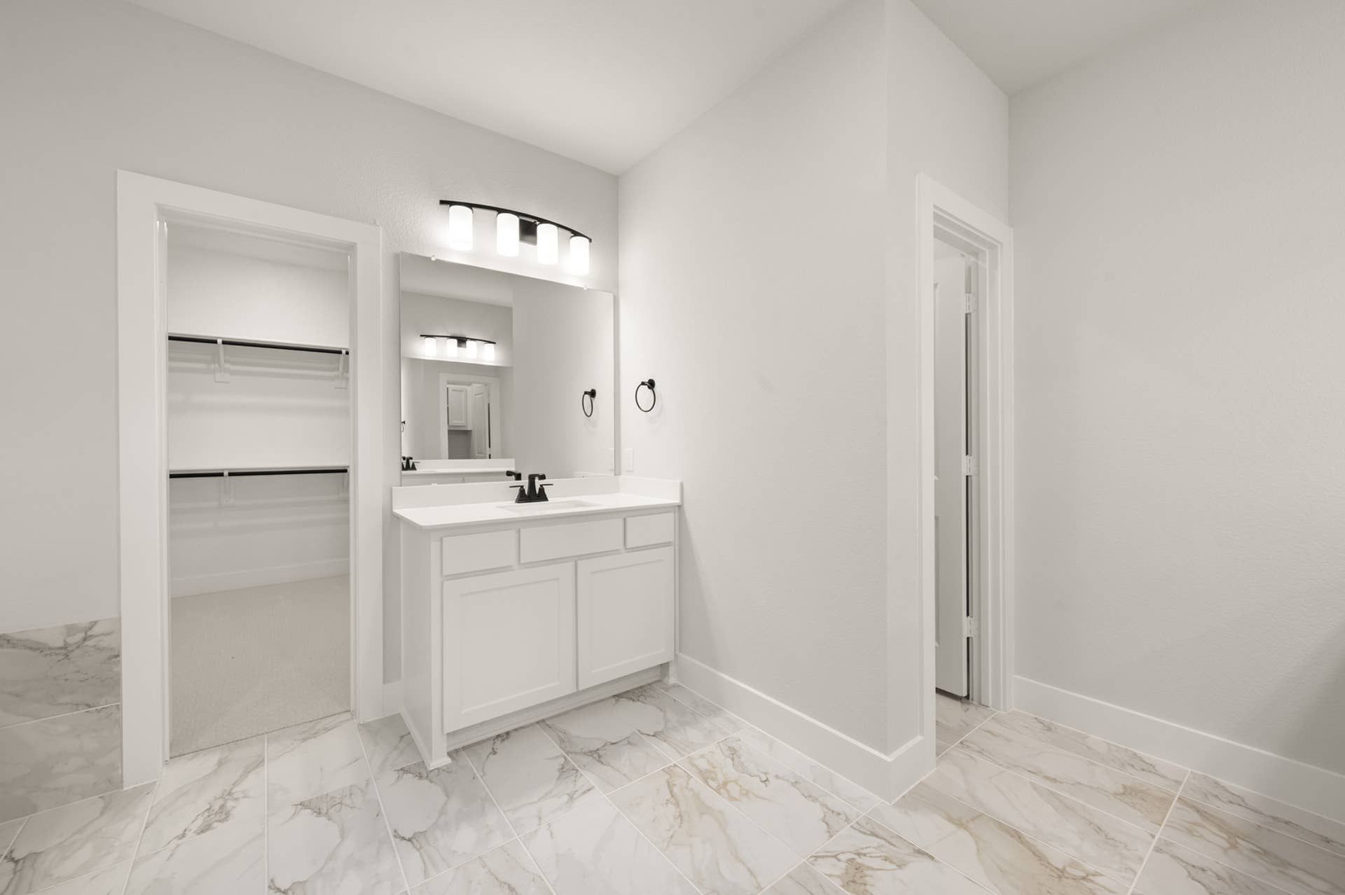 Spacious bathroom with white vanity, large mirror, and walk-in closet.