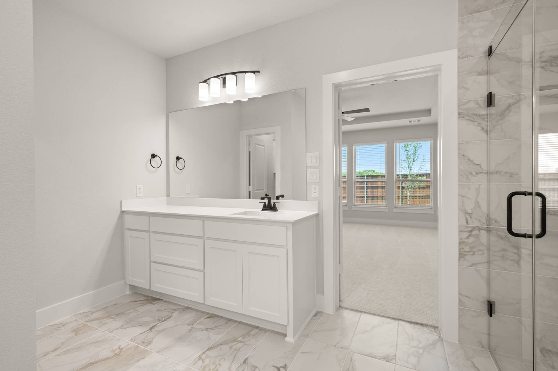 Modern bathroom with white vanity, marble tile, and glass shower door.