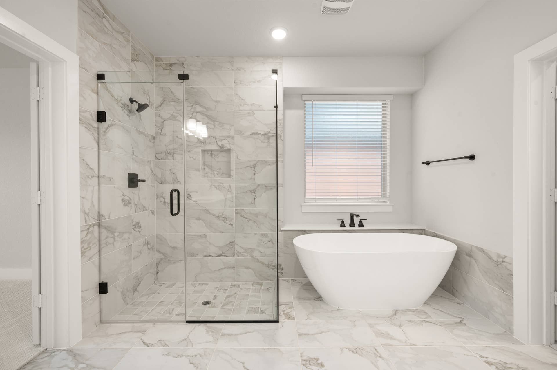 Luxurious bathroom with marble tiles, glass shower, and freestanding bathtub.
