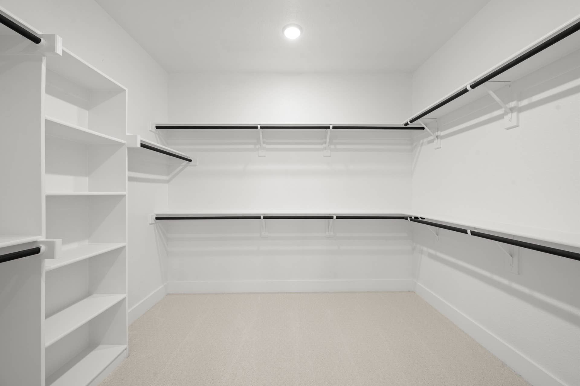 Spacious primary suite walk-in closet with shelving and ample hanging space.