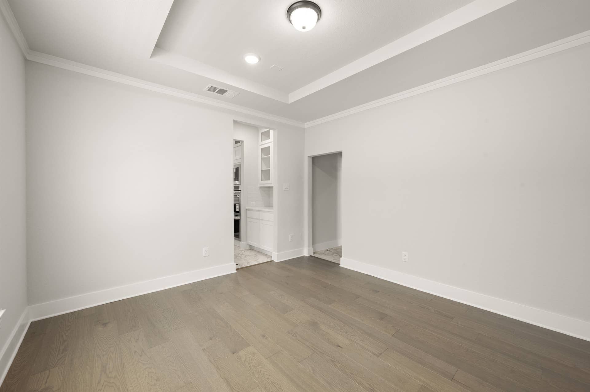 Spacious dining room with tray ceiling and wood flooring.