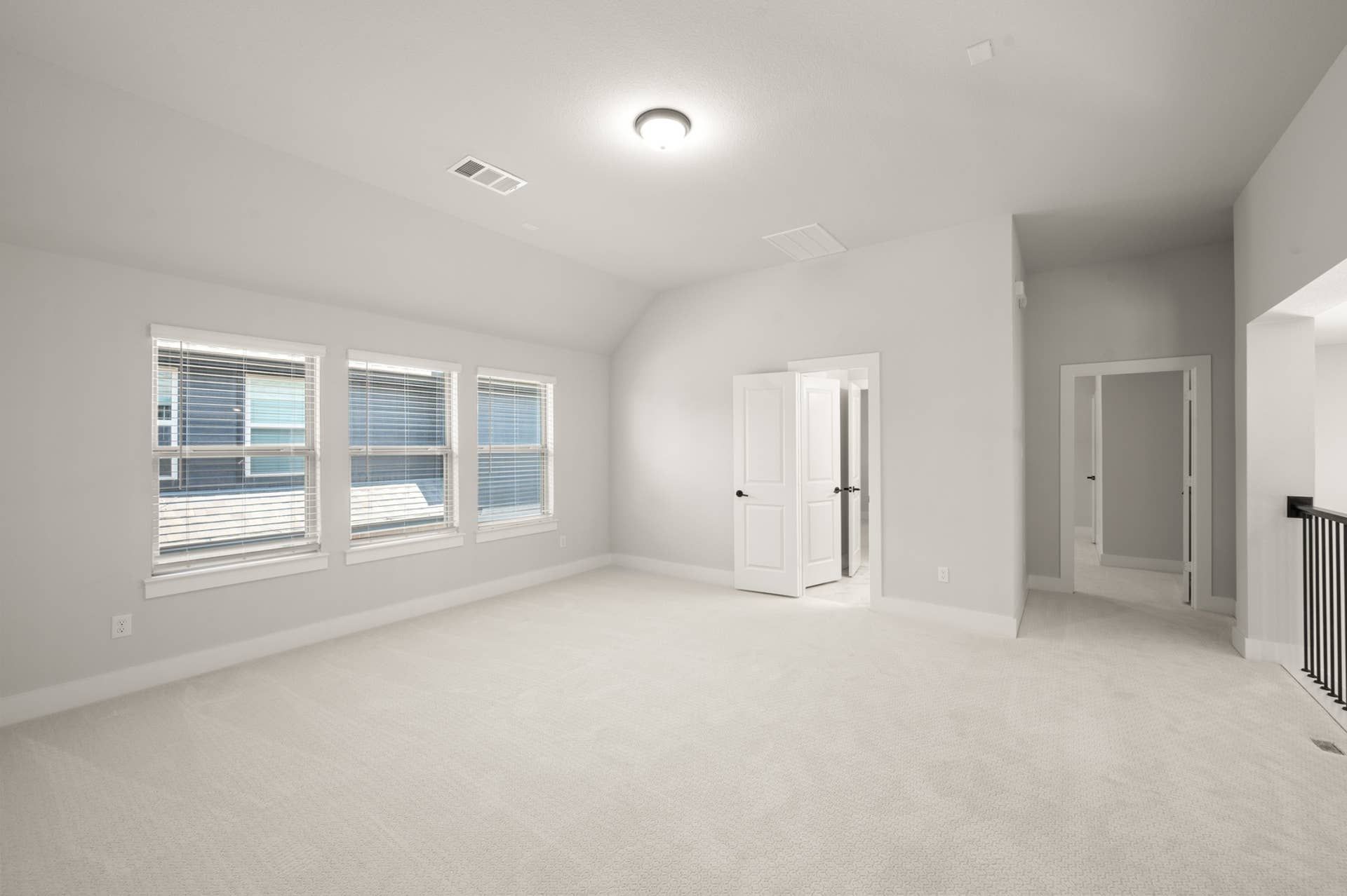 Spacious, carpeted game room with large windows and neutral walls.