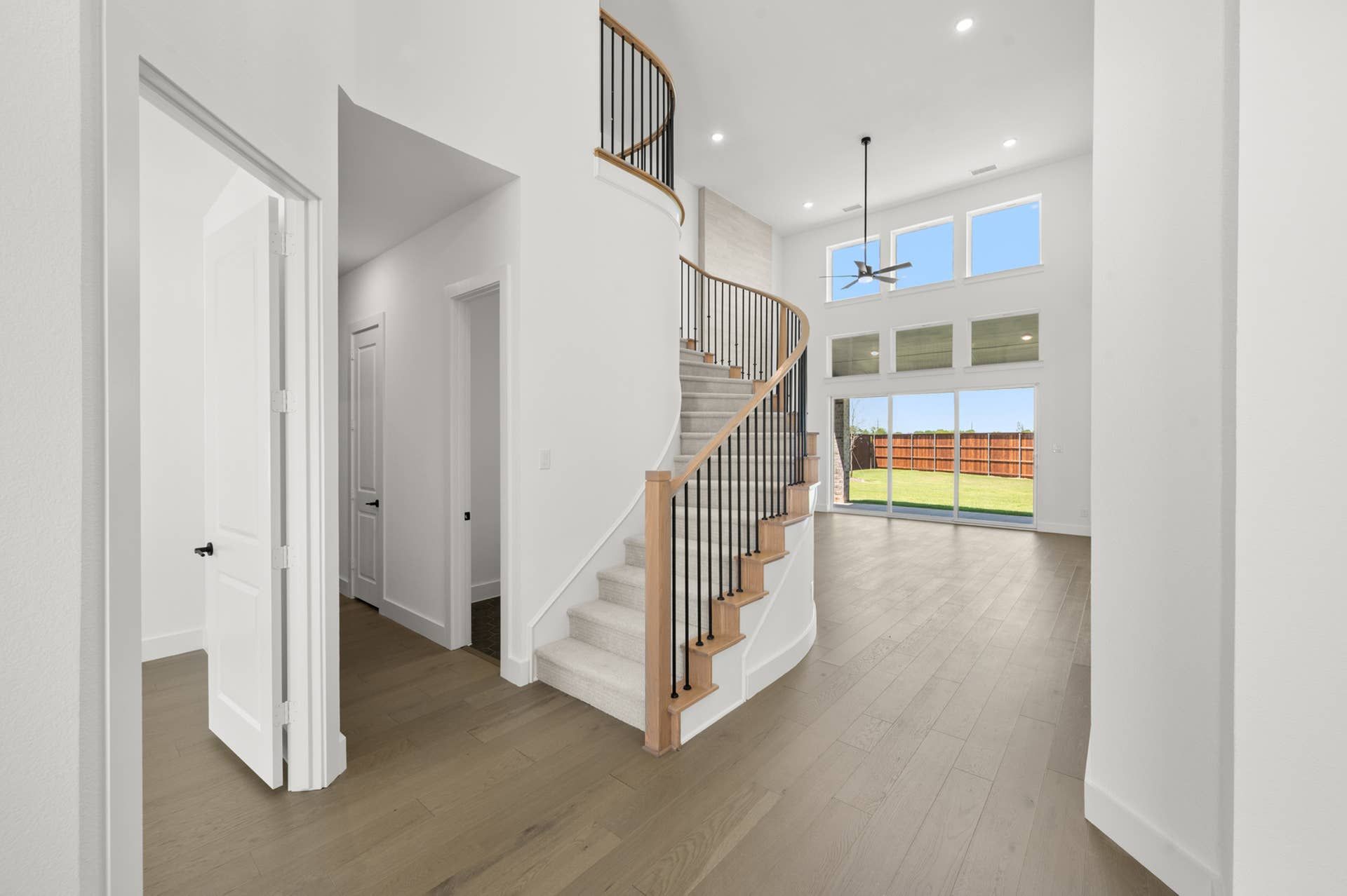 Elegant entryway with curved staircase and large windows overlooking the backyard.