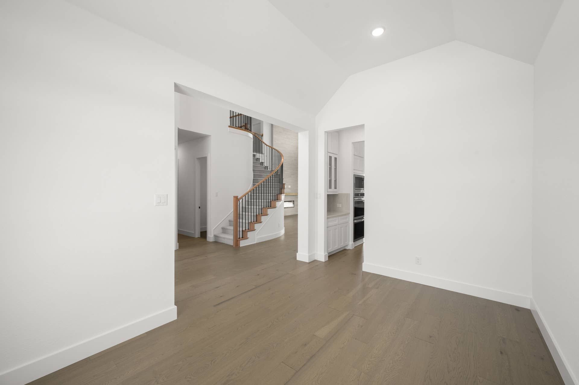 Open interior with wooden floors and elegant spiral staircase.