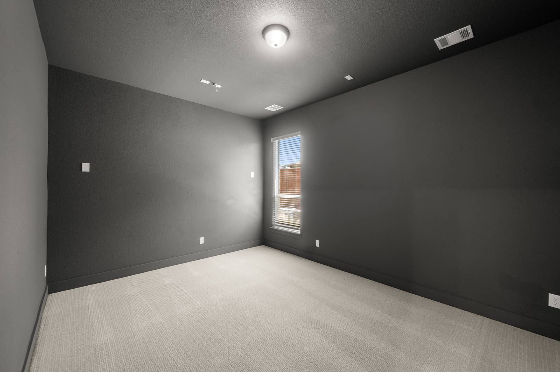 Modern media room with dark walls and single window.