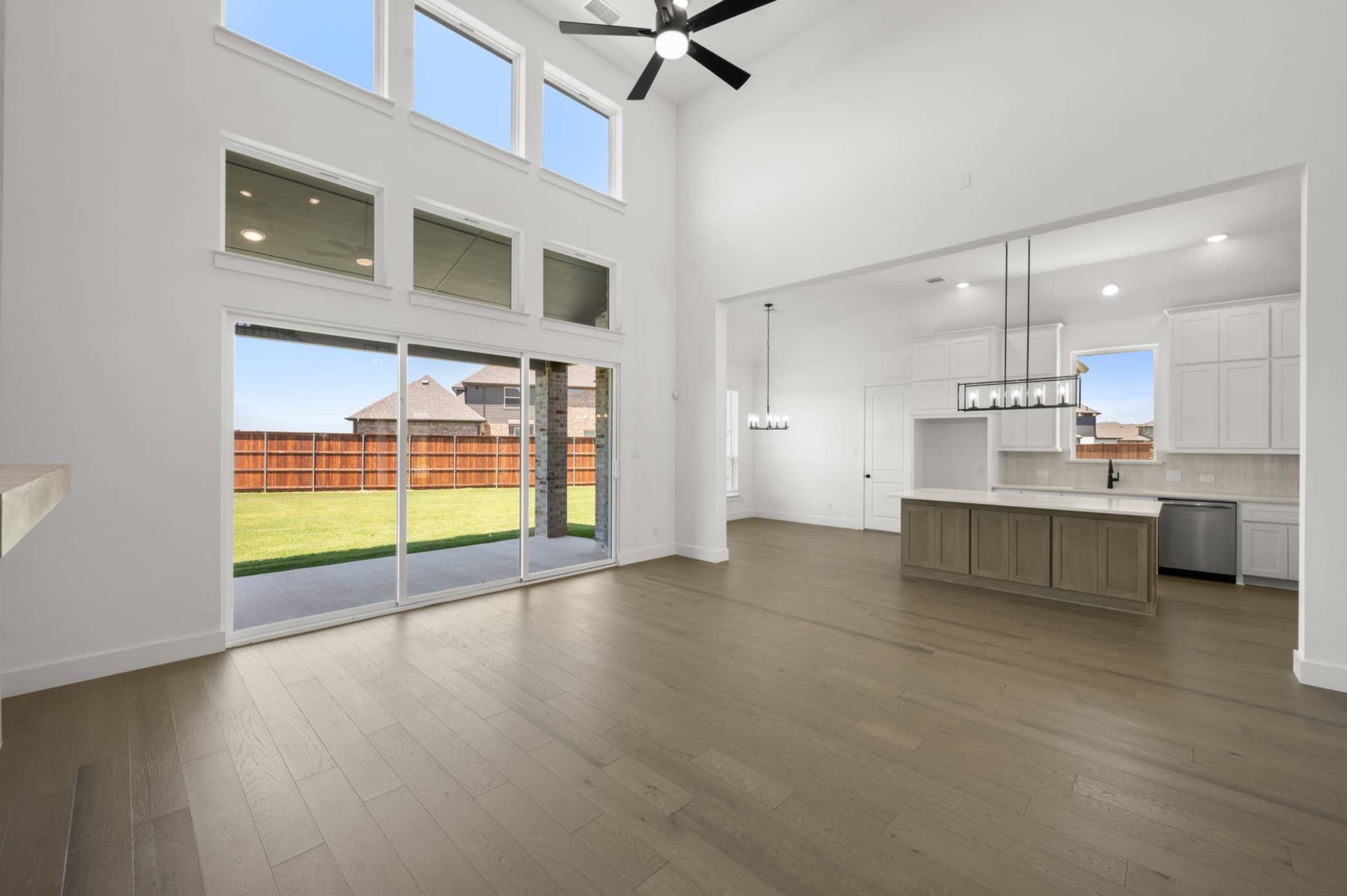 Spacious living room with high ceilings, large windows, and open kitchen layout.