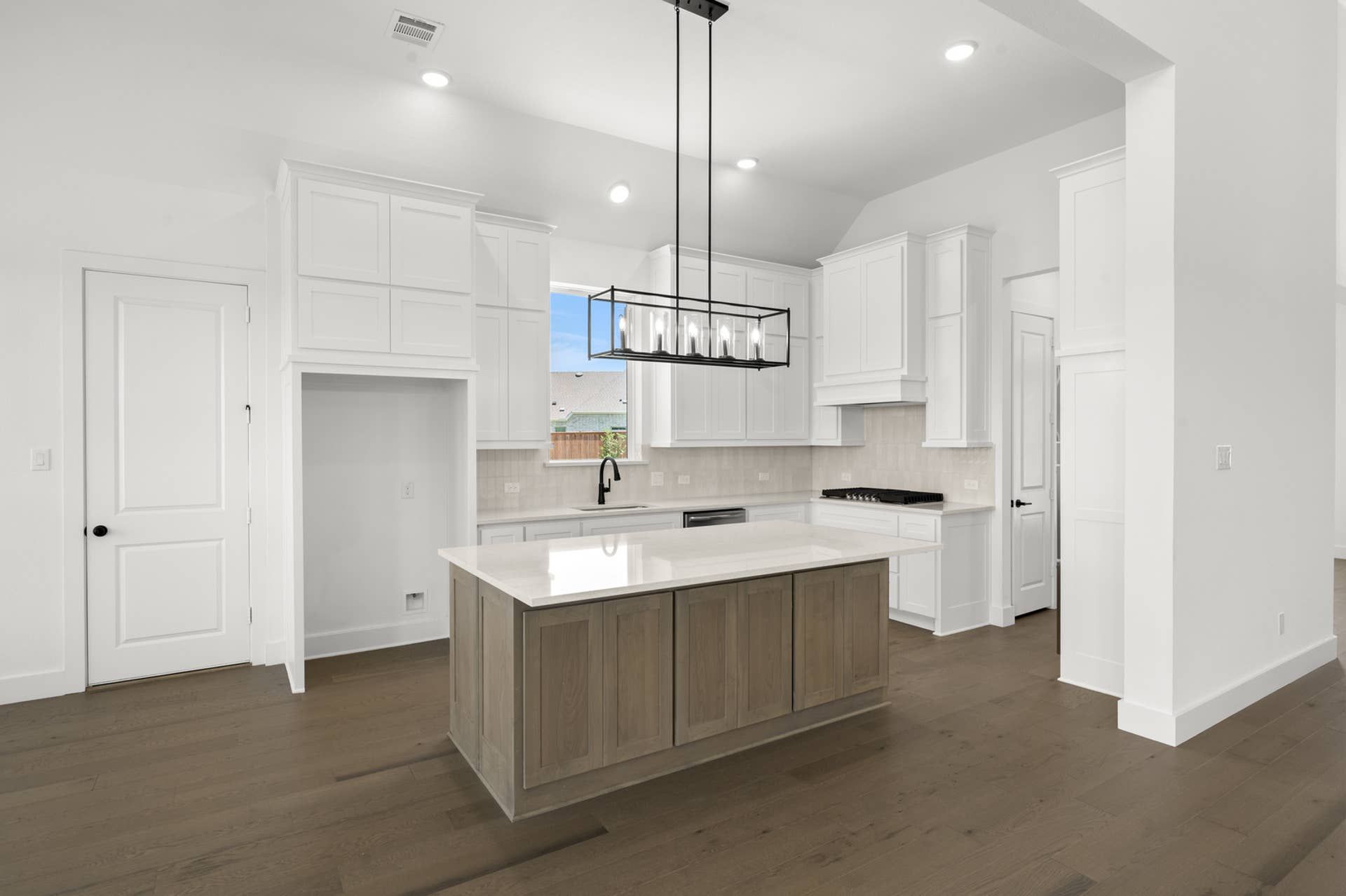 Modern kitchen with white cabinetry, wood island, and pendant lighting.
