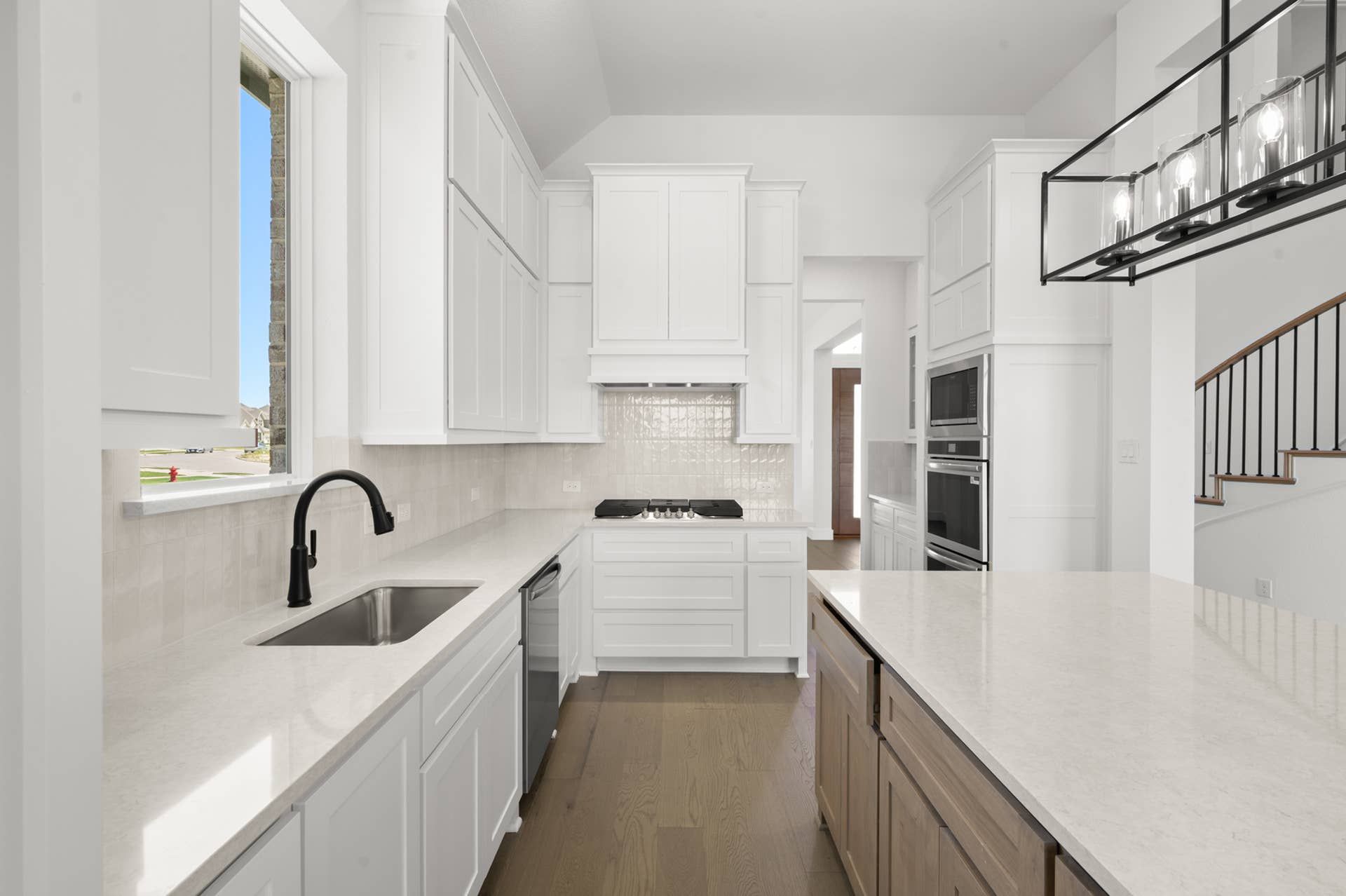 Modern kitchen with white cabinetry, island, and stainless steel appliances.