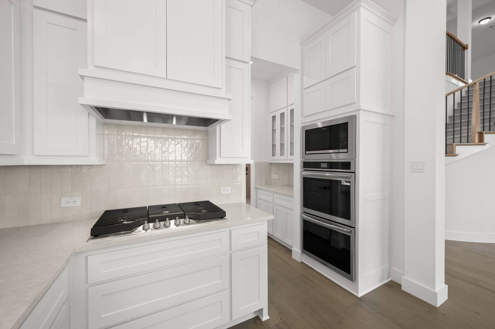 Modern kitchen with white cabinetry, built-in ovens, and sleek cooktop.