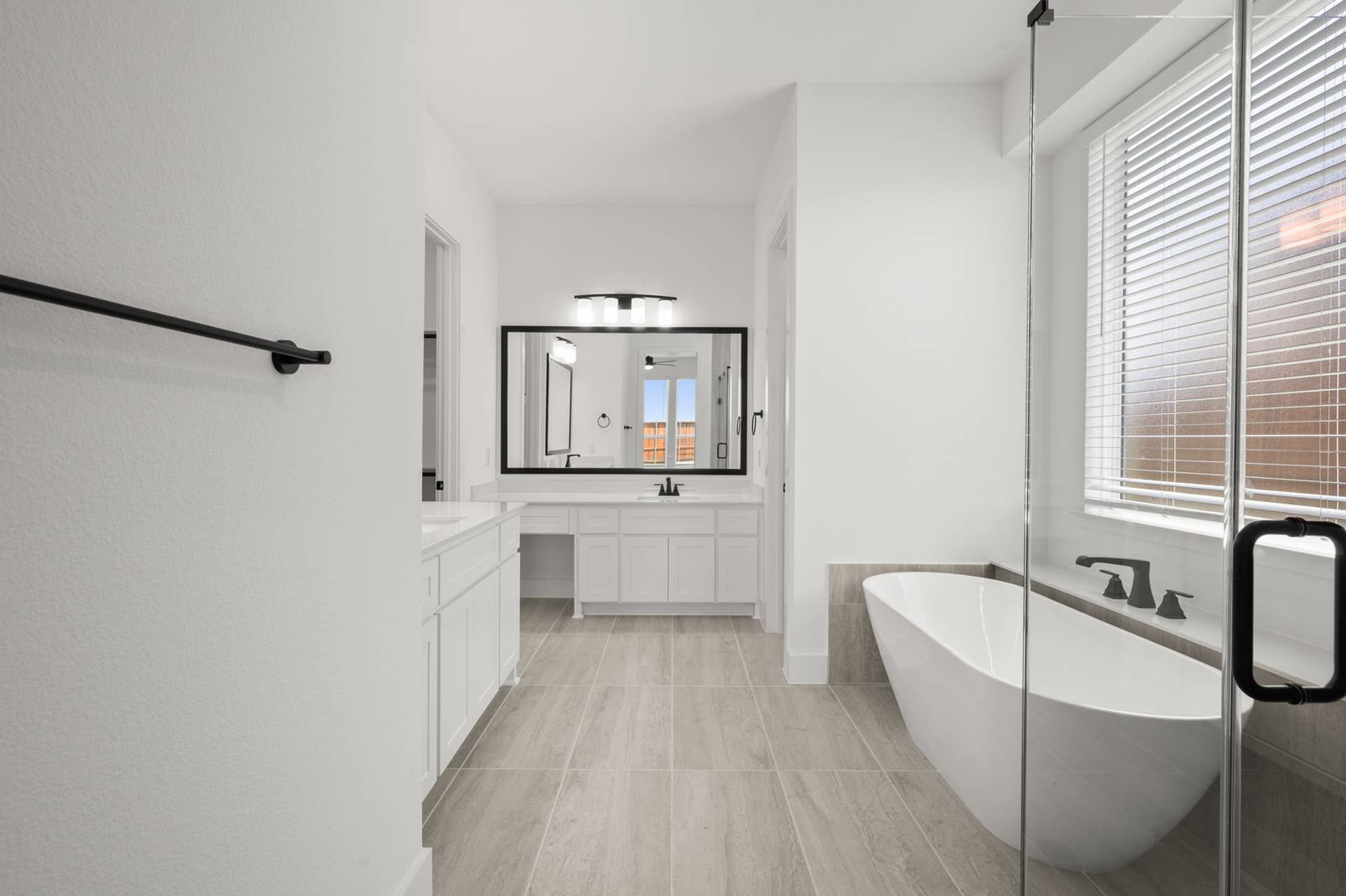 Modern bathroom with freestanding tub, large mirror, and sleek fixtures.