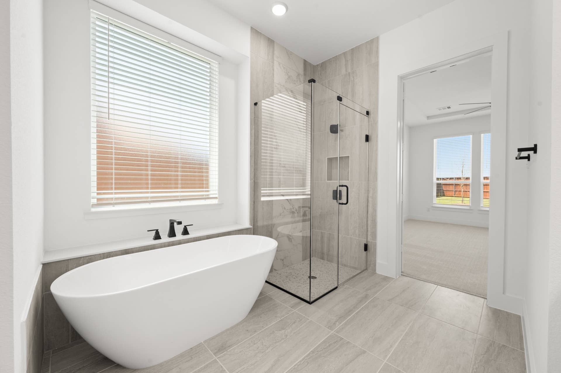 Primary suite bathroom with freestanding tub and glass-enclosed shower.