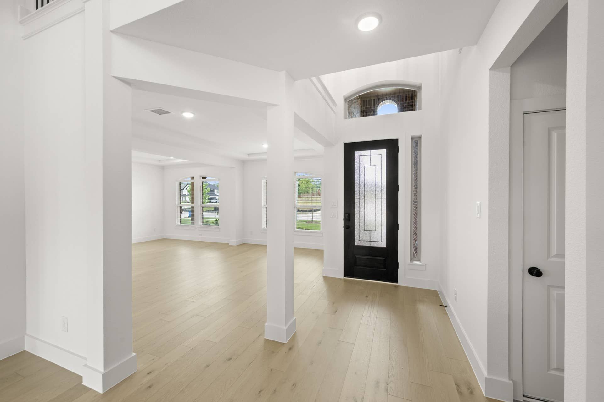 Spacious entry with modern door and light wood flooring.