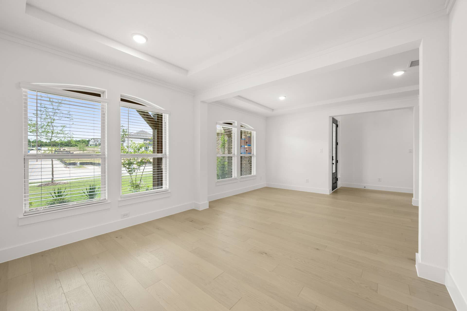 Interior flex space with large windows and light wood flooring.