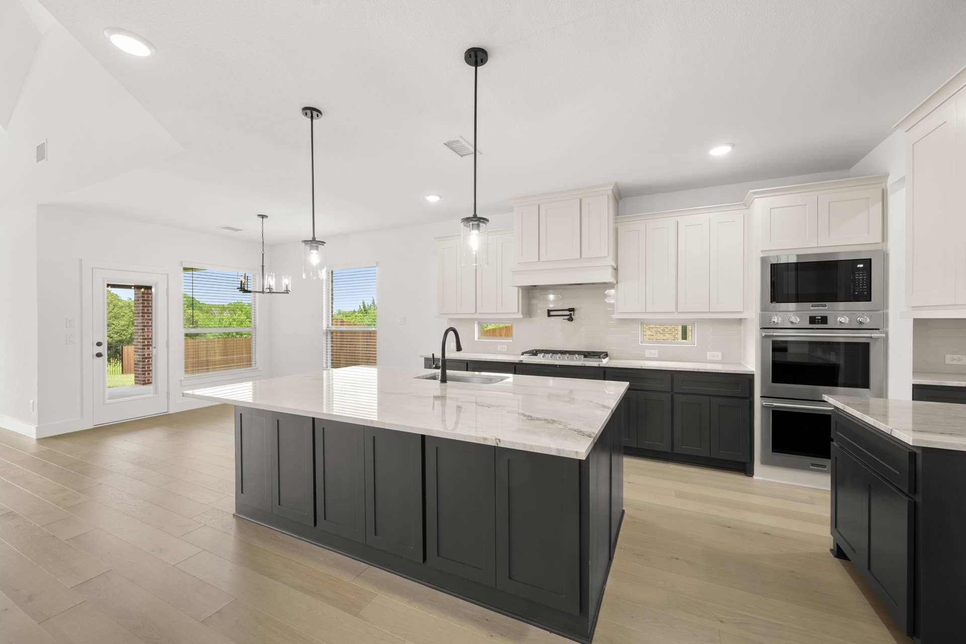 Modern kitchen with large island, pendant lighting, and stainless steel appliances.