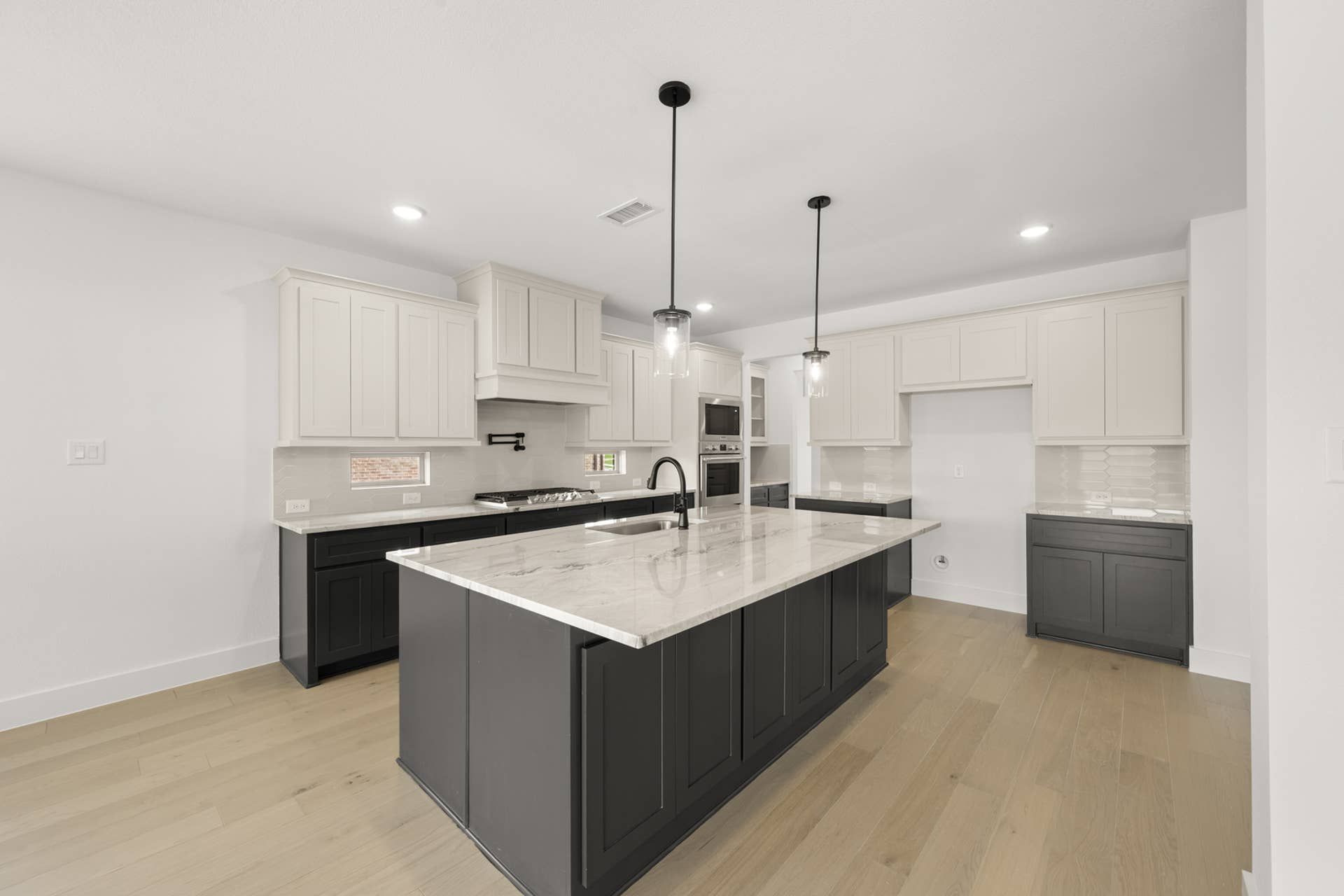 Modern kitchen with marble island, pendant lighting, and sleek cabinetry.
