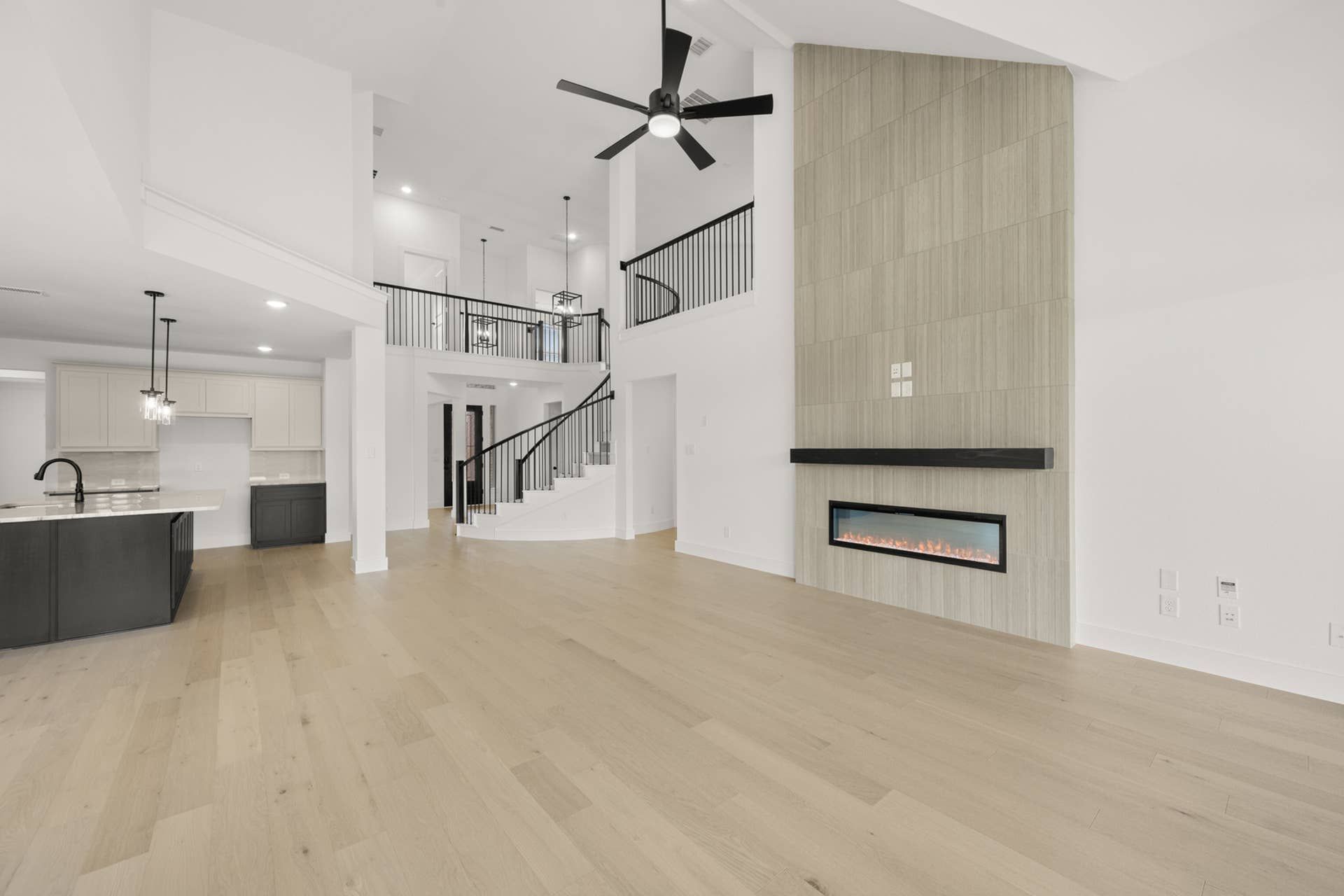 Spacious modern living room with open floor plan, fireplace, and staircase.