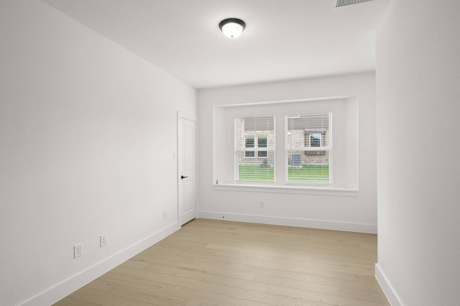 Bright study room with large window and hardwood flooring.