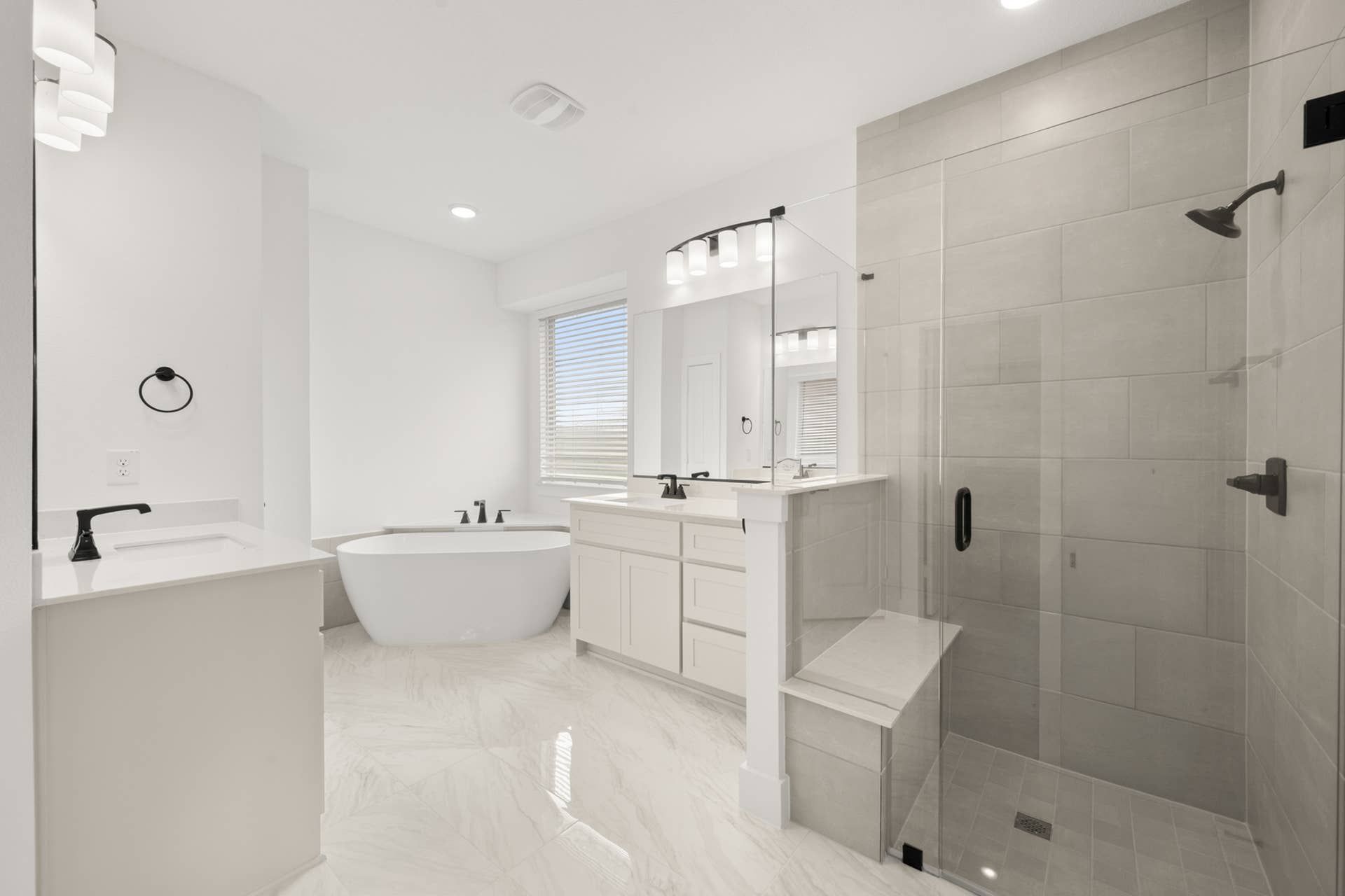 Luxurious primary suite bathroom with freestanding tub and glass-enclosed shower.