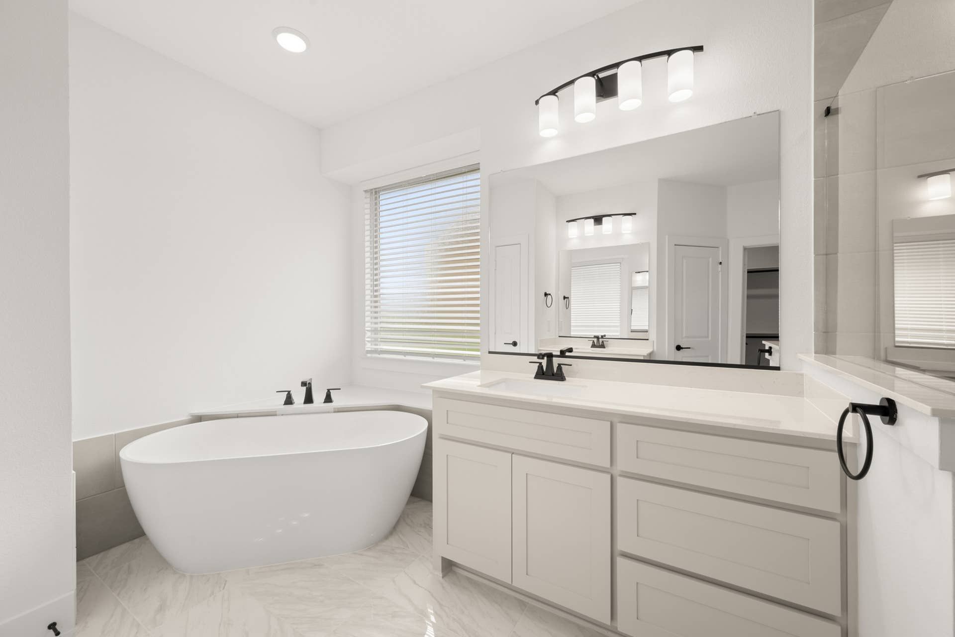 Modern primary suite bathroom with freestanding tub and dual-sink vanity.