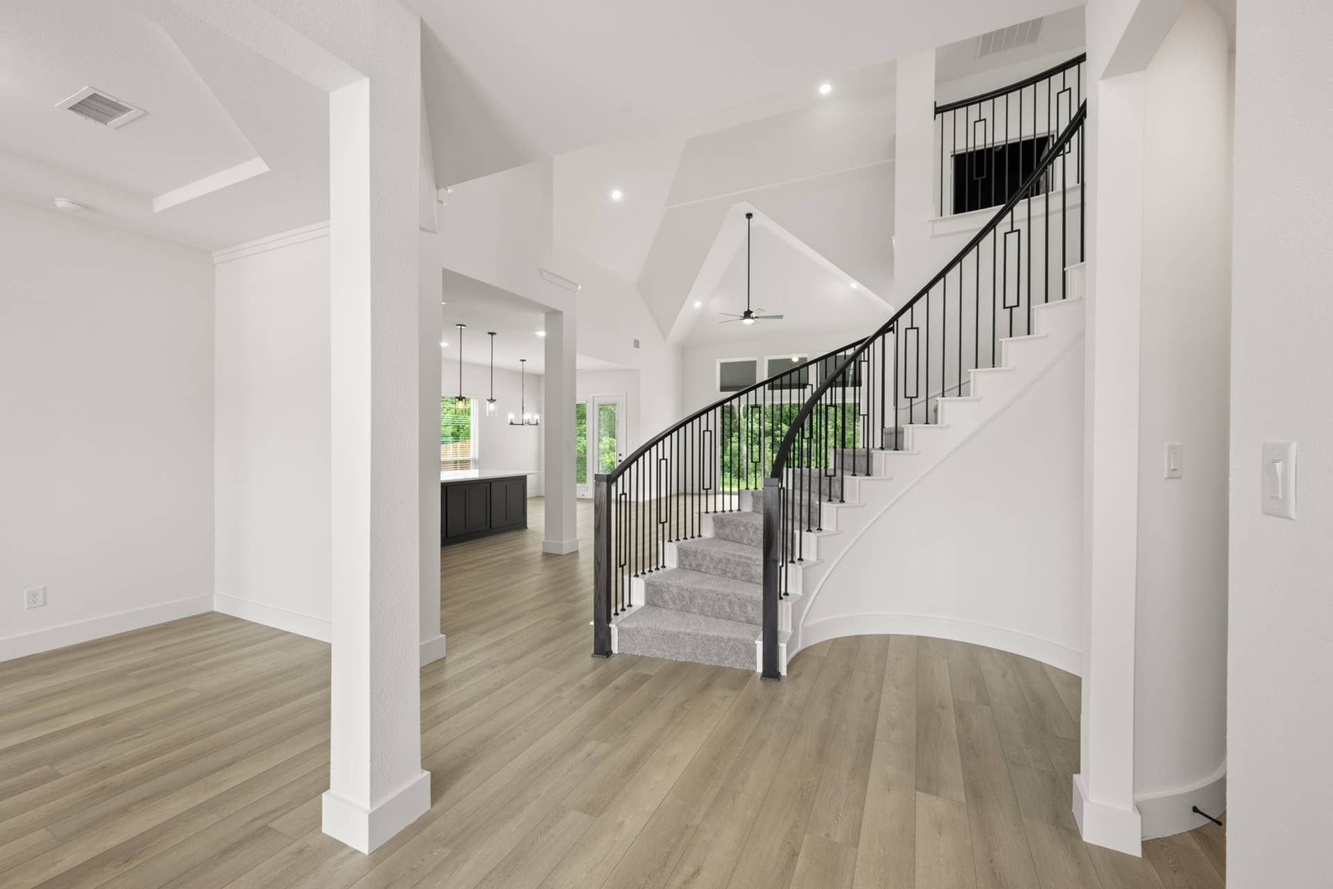 Elegant foyer with curved staircase and open-concept living space.