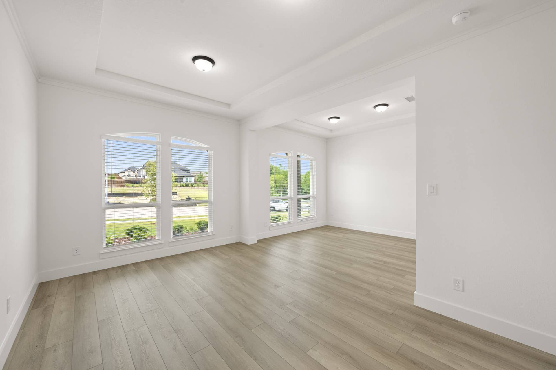 Bright, open flex space with large windows and wood flooring.