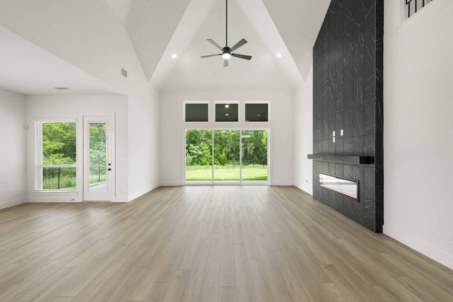 Spacious living room with vaulted ceiling, modern fireplace, and large windows.