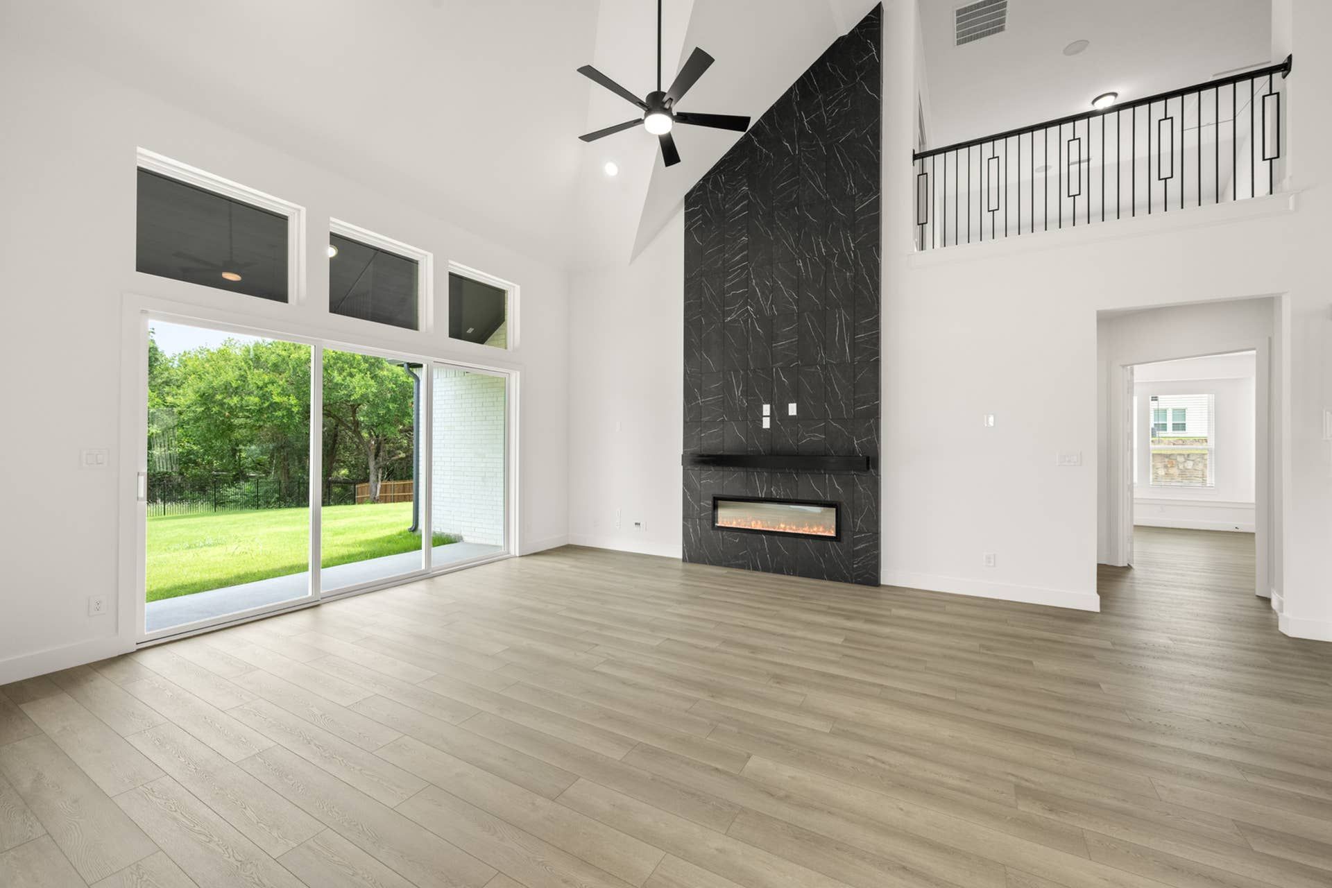 Spacious living room with large windows, modern fireplace, and wood flooring.