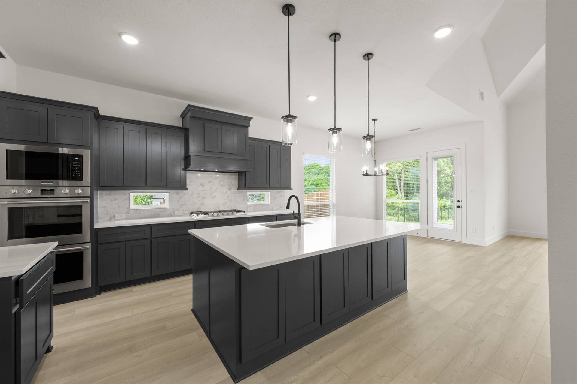 Modern kitchen with dark cabinets, large island, and pendant lighting.