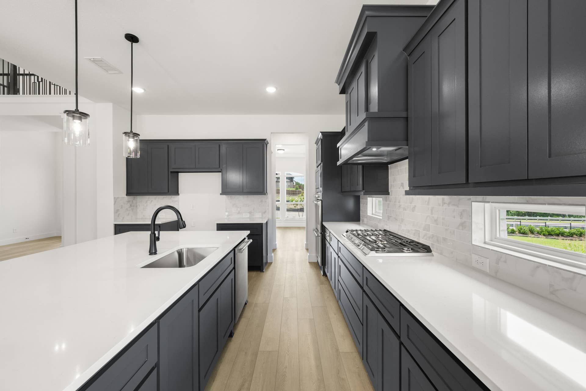 Modern kitchen with dark cabinetry, white countertops, and pendant lighting.