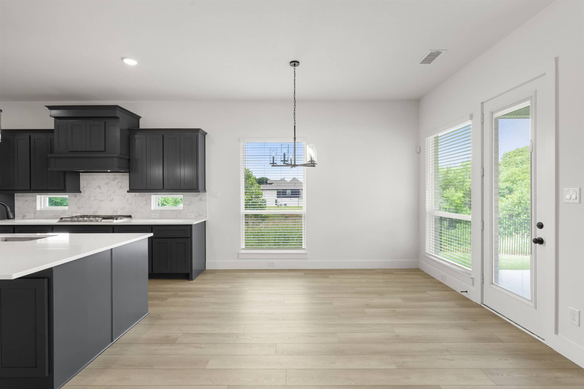 Modern kitchen and dining area with dark cabinets and large windows.