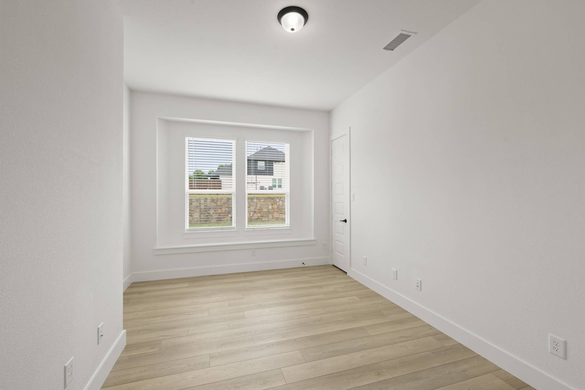 Bright study room with wood flooring and large window.