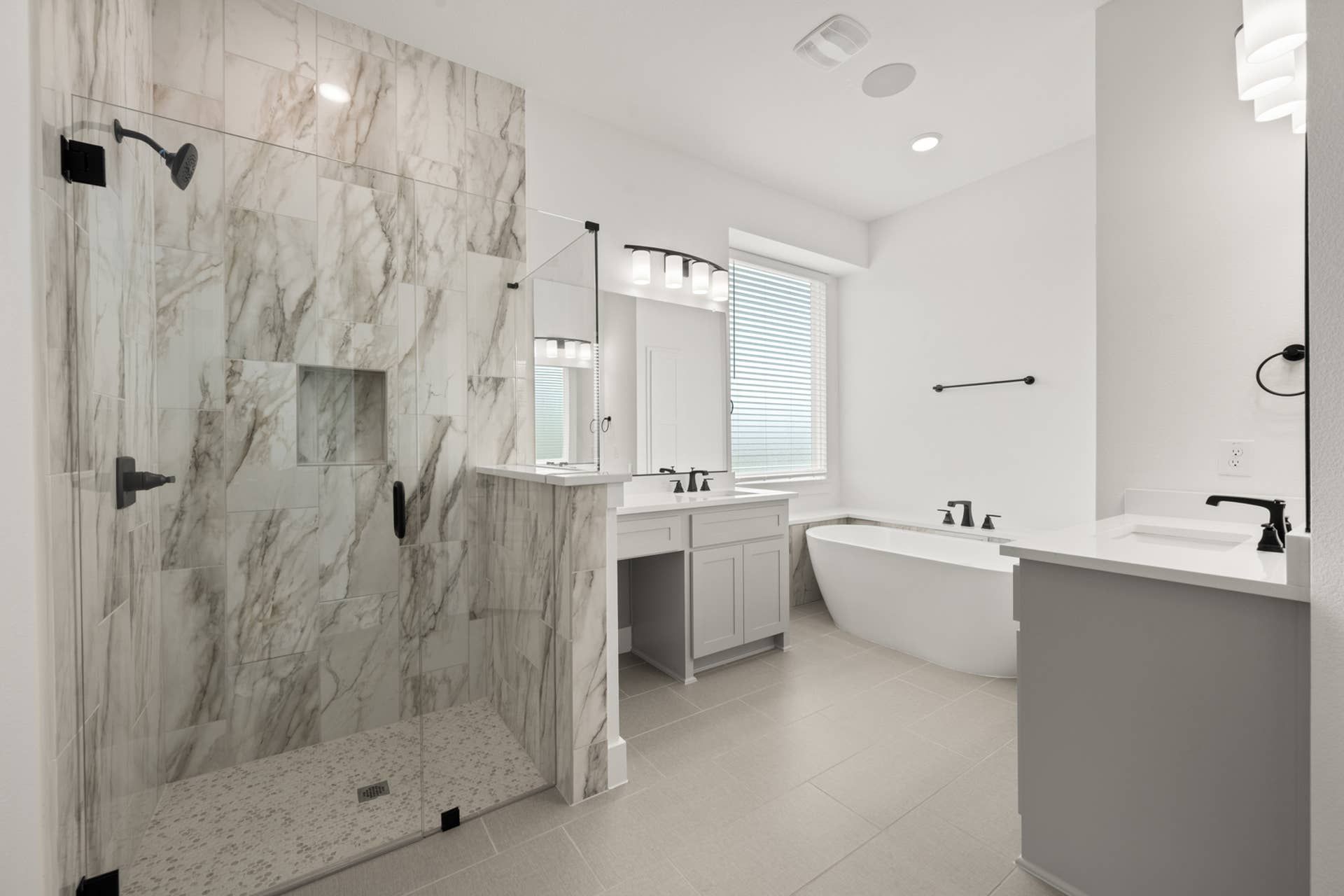 Luxurious bathroom with marble shower, freestanding tub, and dual vanities.