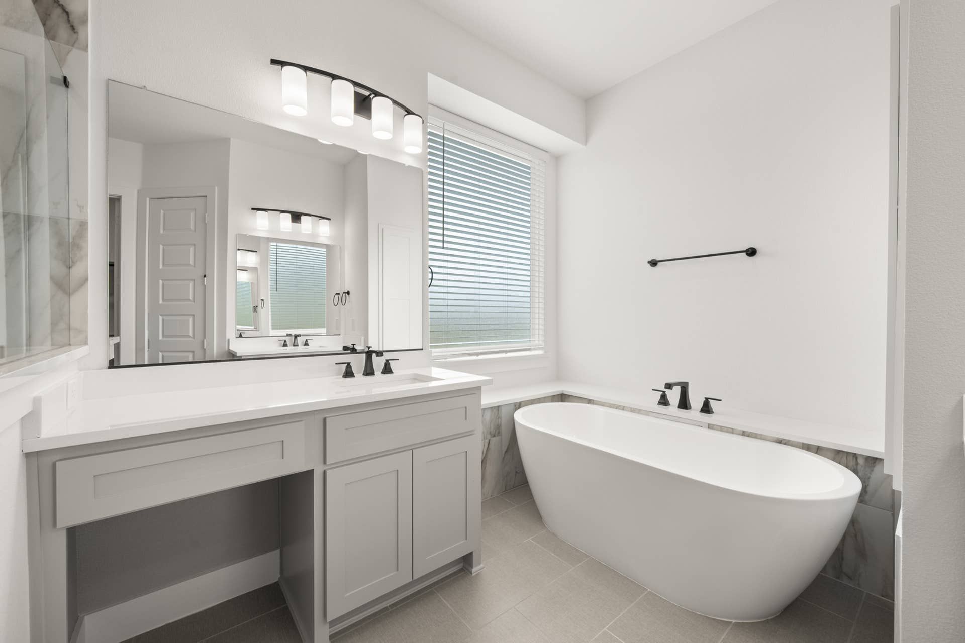 Elegant bathroom with freestanding tub, large mirror, and modern lighting.