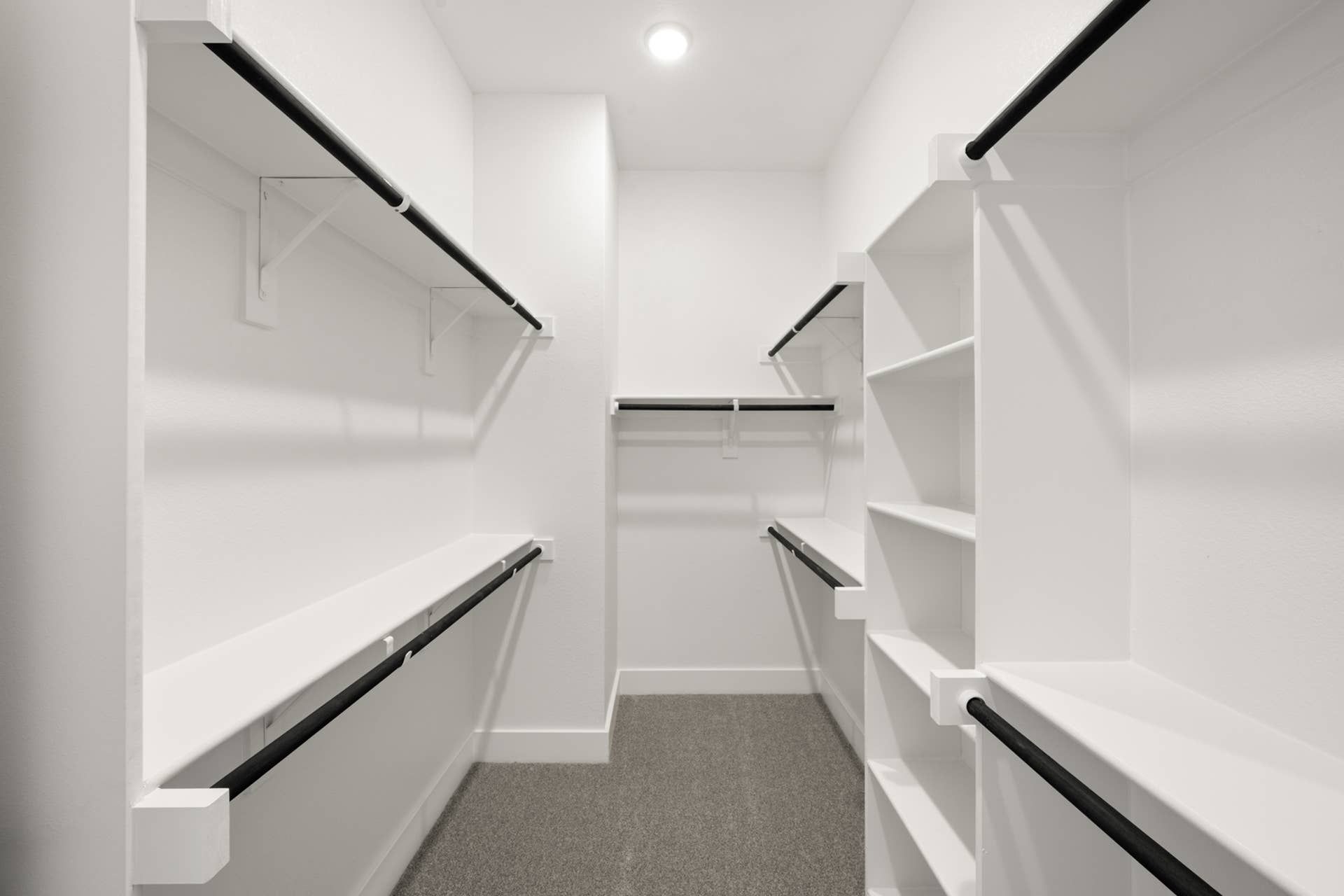 Spacious walk-in closet with white shelving and ample hanging space.