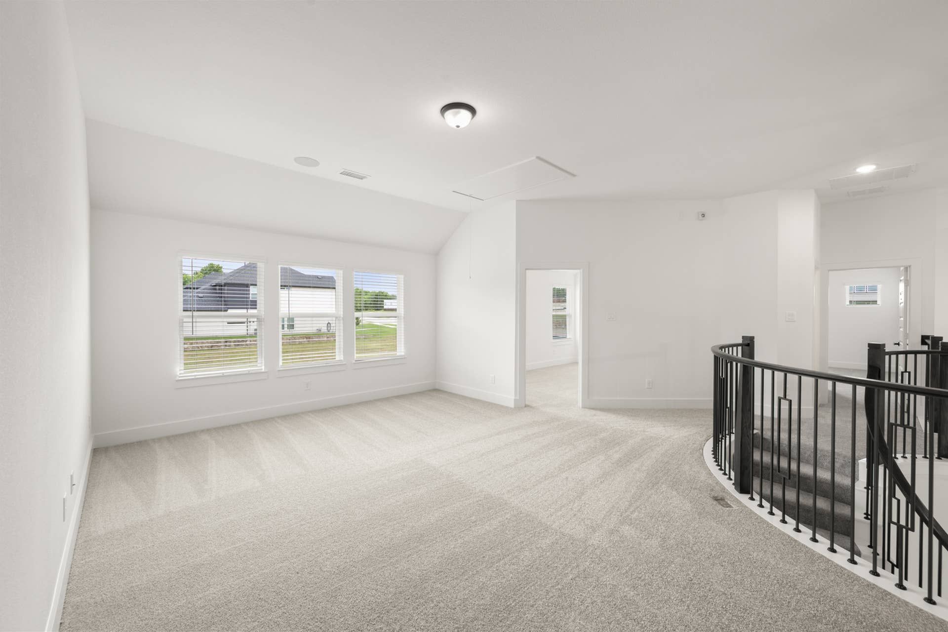 Spacious game room with carpet flooring and large windows.