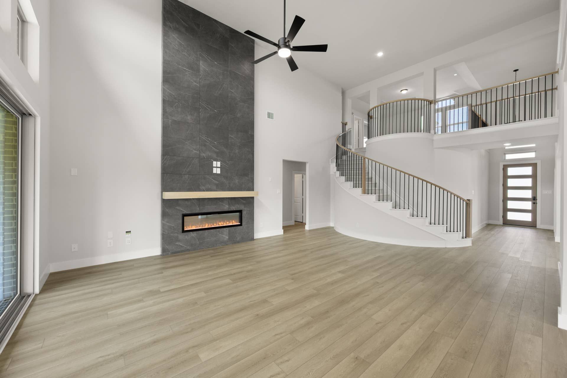 Spacious living room with modern fireplace and elegant curved staircase.