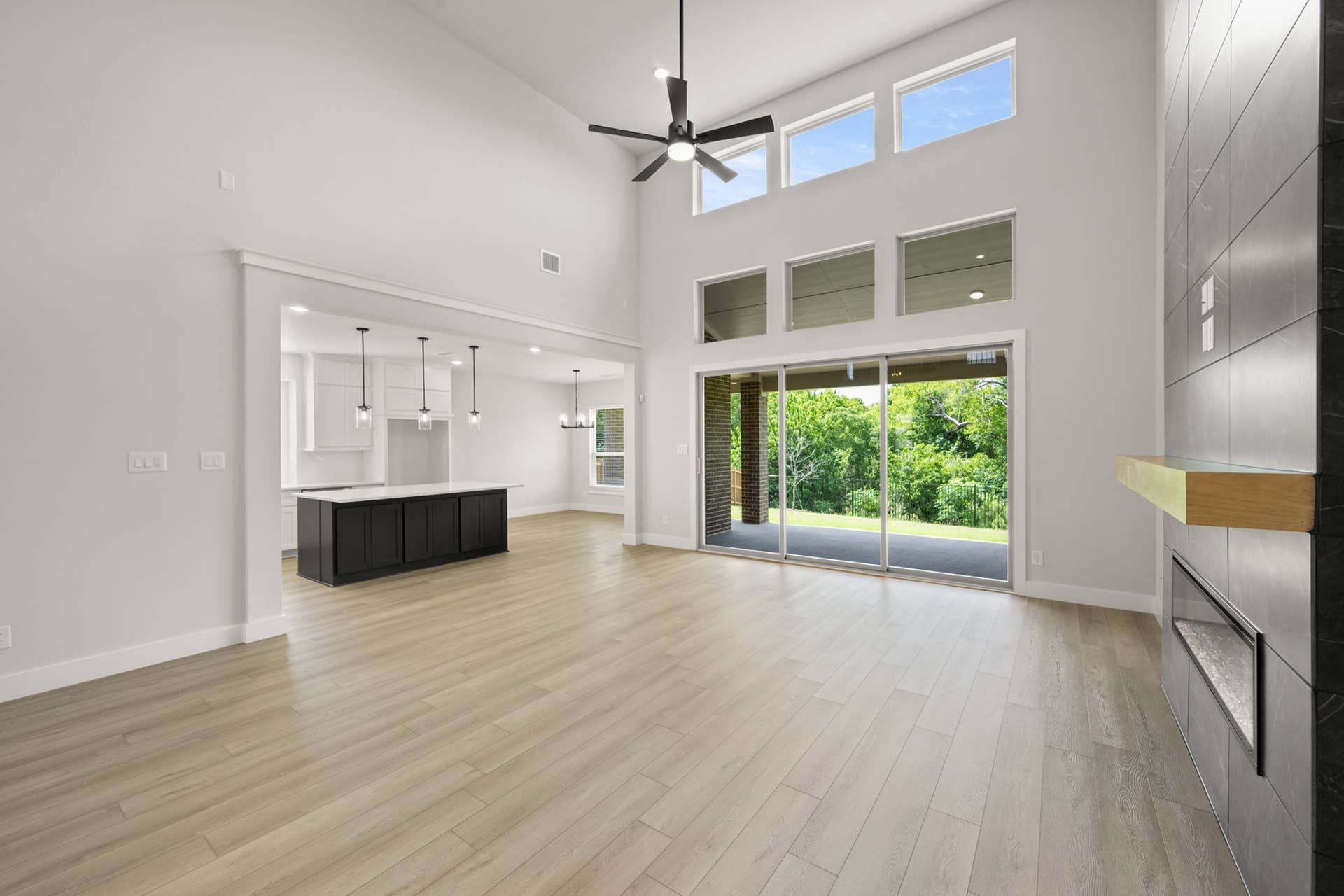 Spacious living room with high ceilings, large windows, and open kitchen area.