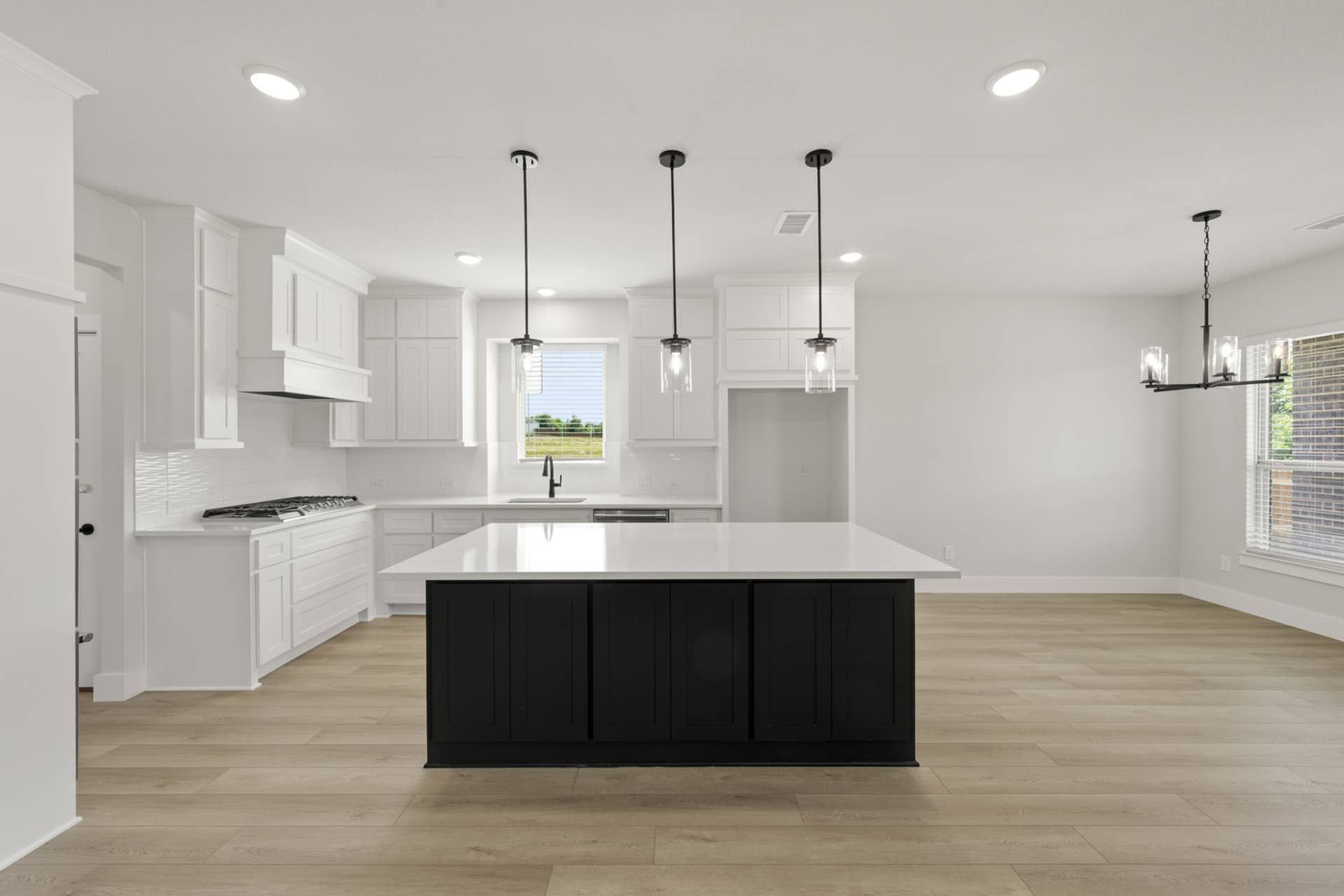 Modern kitchen with white cabinetry, large island, and pendant lighting.