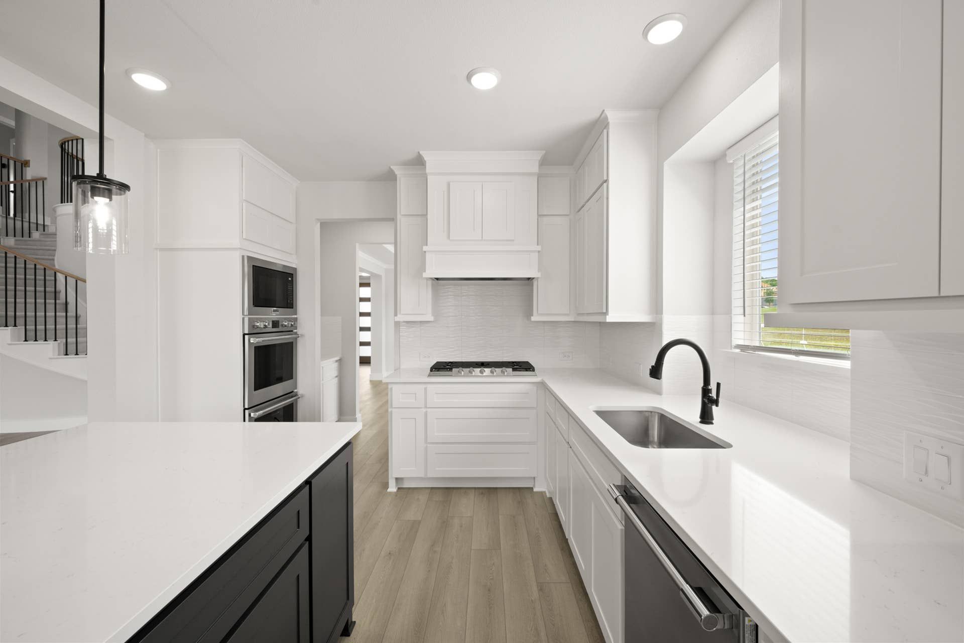 Modern kitchen with white cabinetry, black accents, and stainless steel appliances.