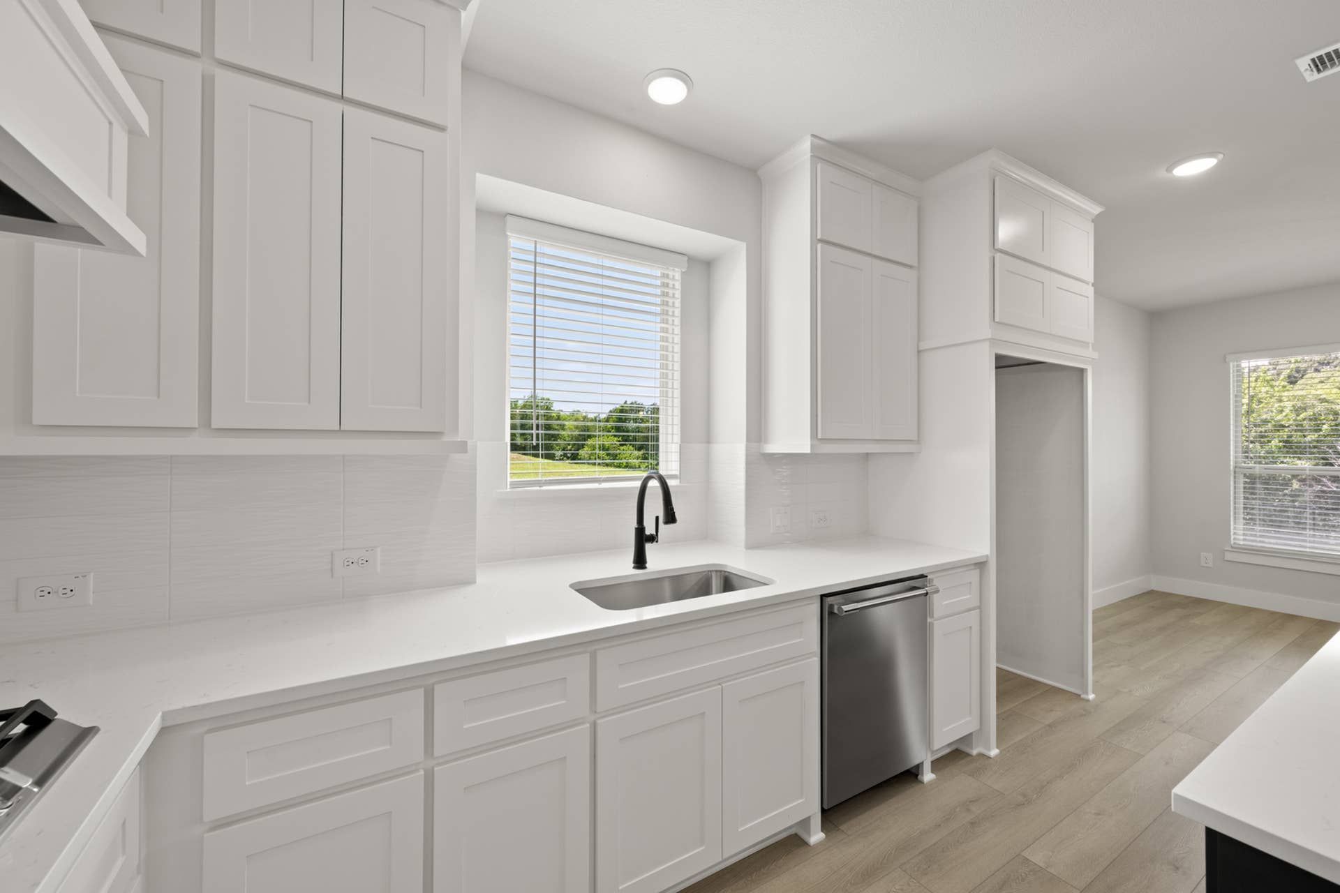 Modern kitchen with white cabinetry, stainless steel appliances, and large window.
