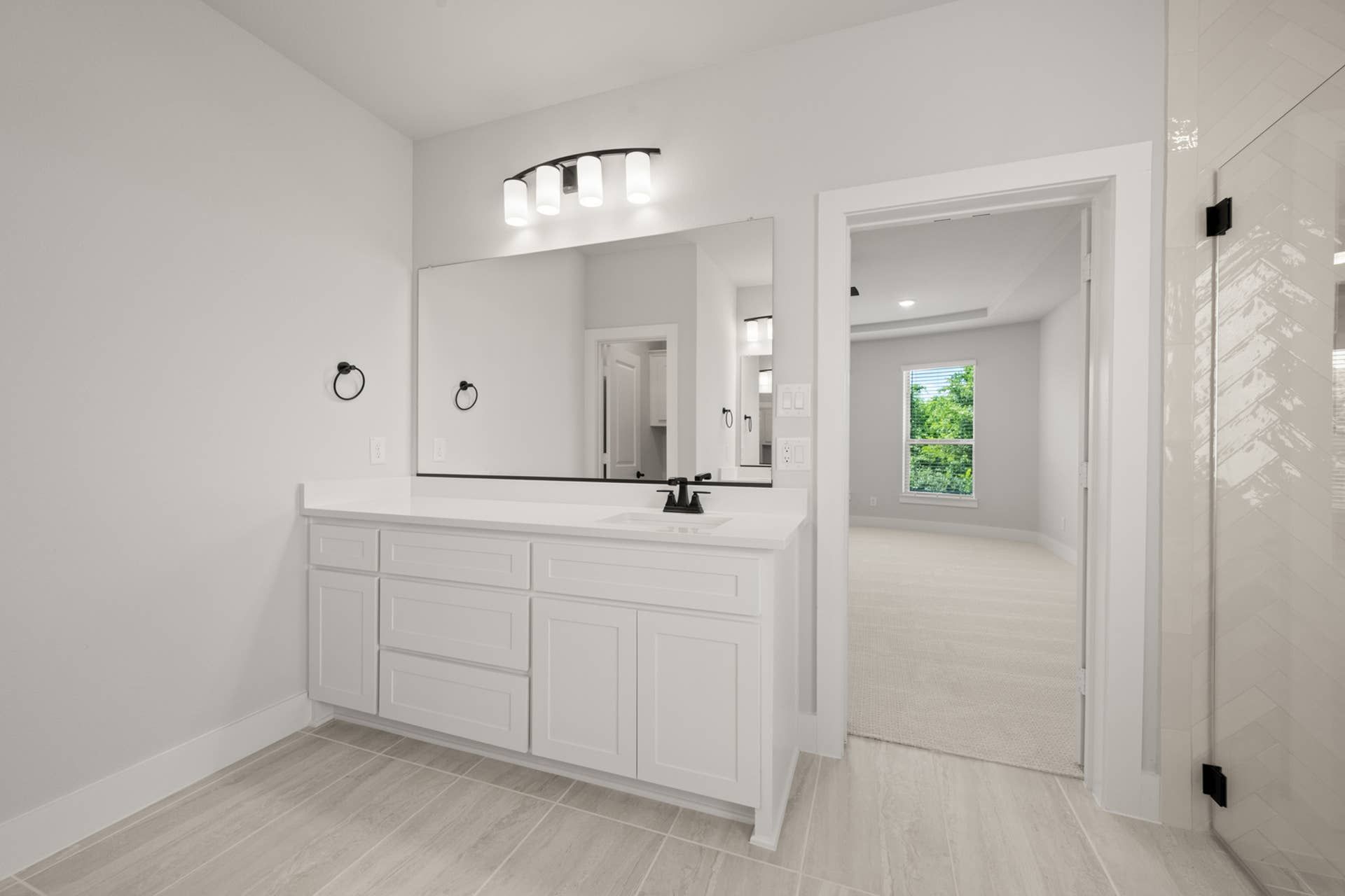 Spacious primary suite bathroom with modern vanity and large mirror.