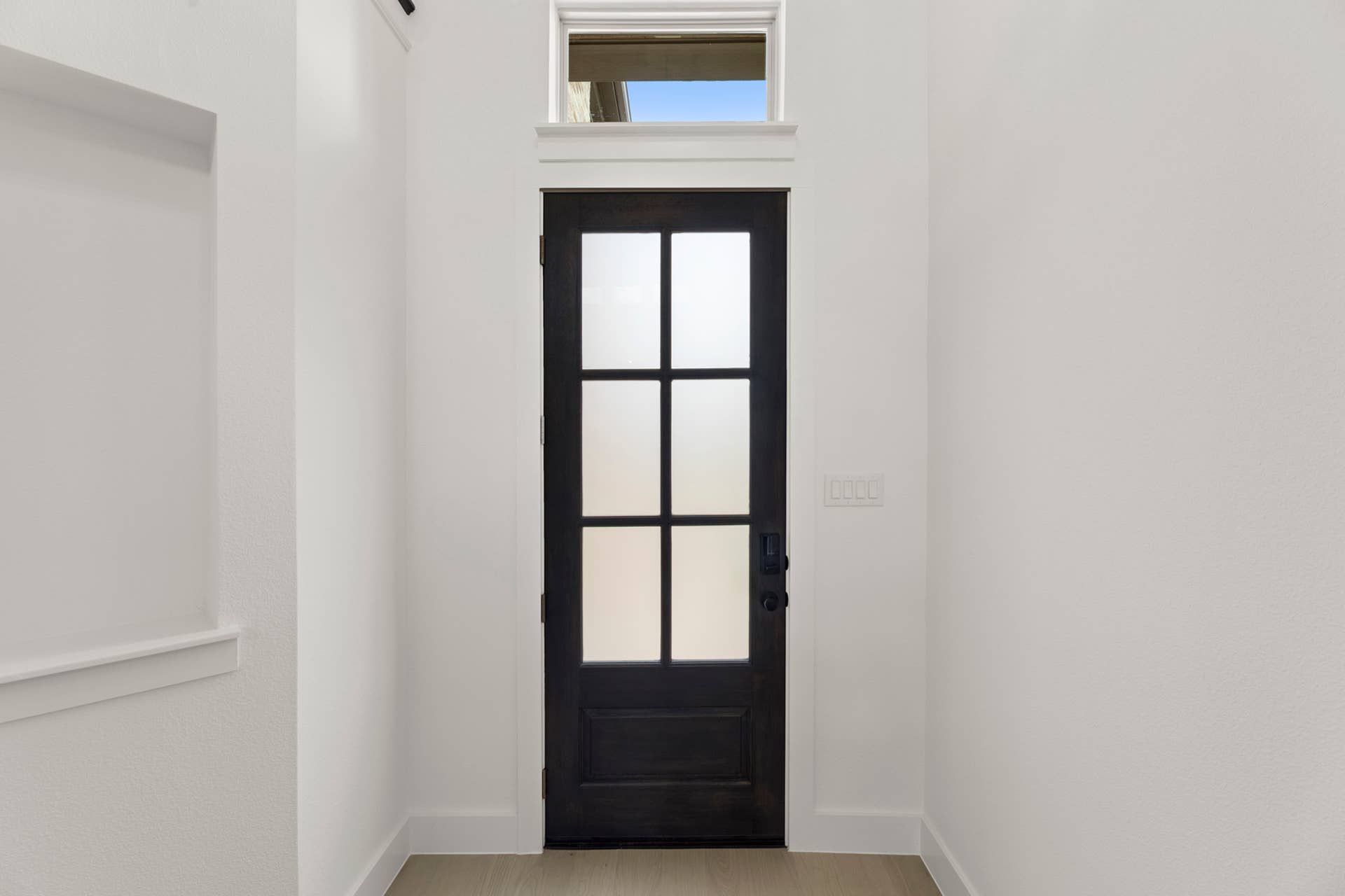 Modern interior entryway with frosted glass door and transom window.
