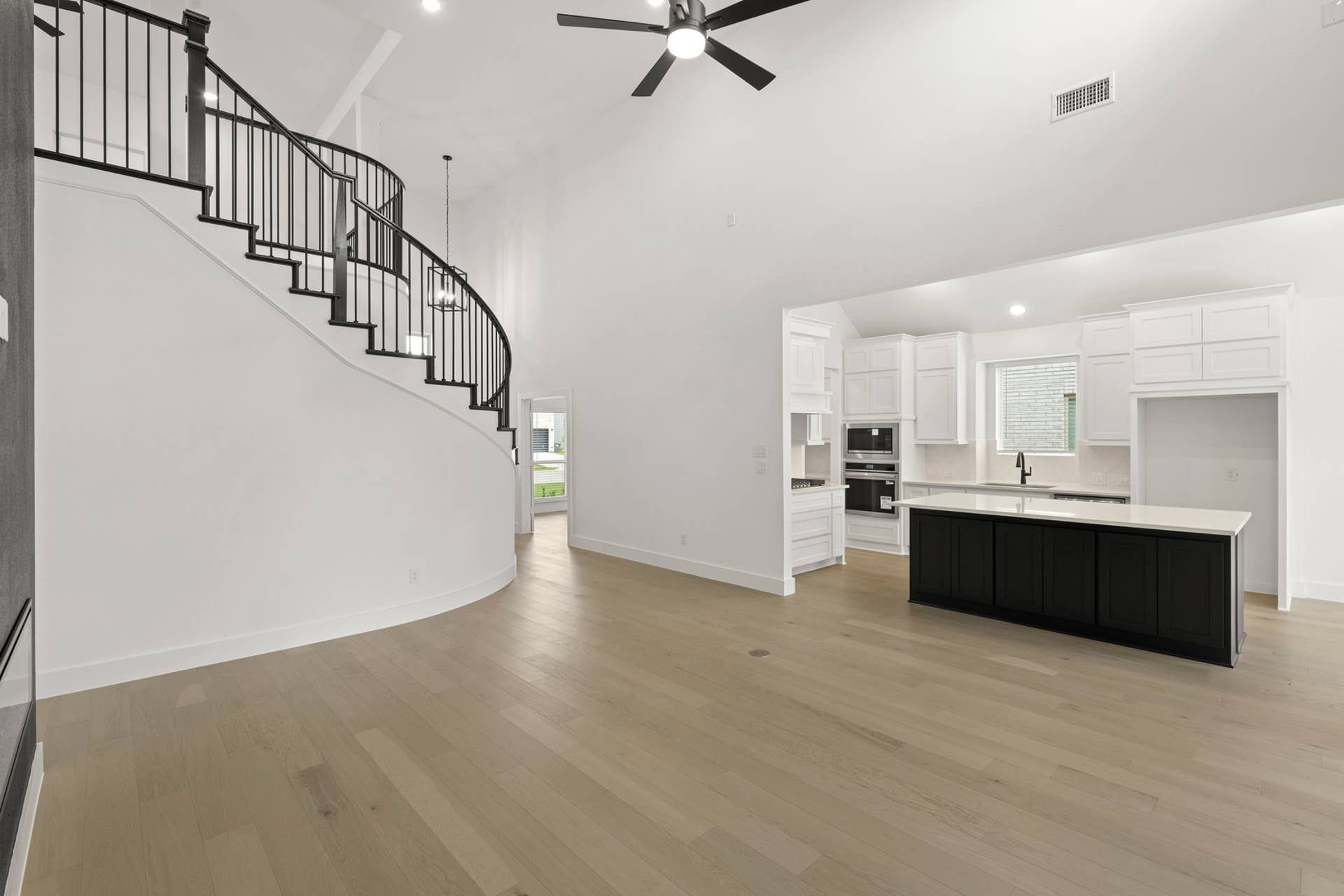 Spacious modern kitchen with island and elegant curved staircase.