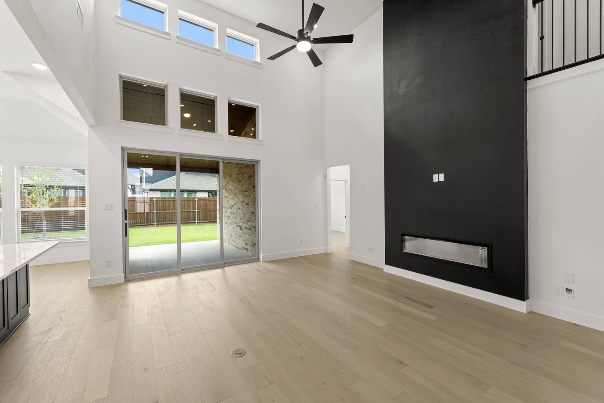 Spacious living room with high ceilings, modern fireplace, and large sliding glass doors.