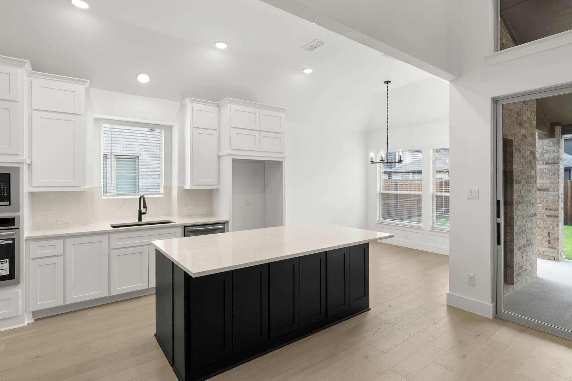 Modern kitchen with white cabinets, black island, and natural light.