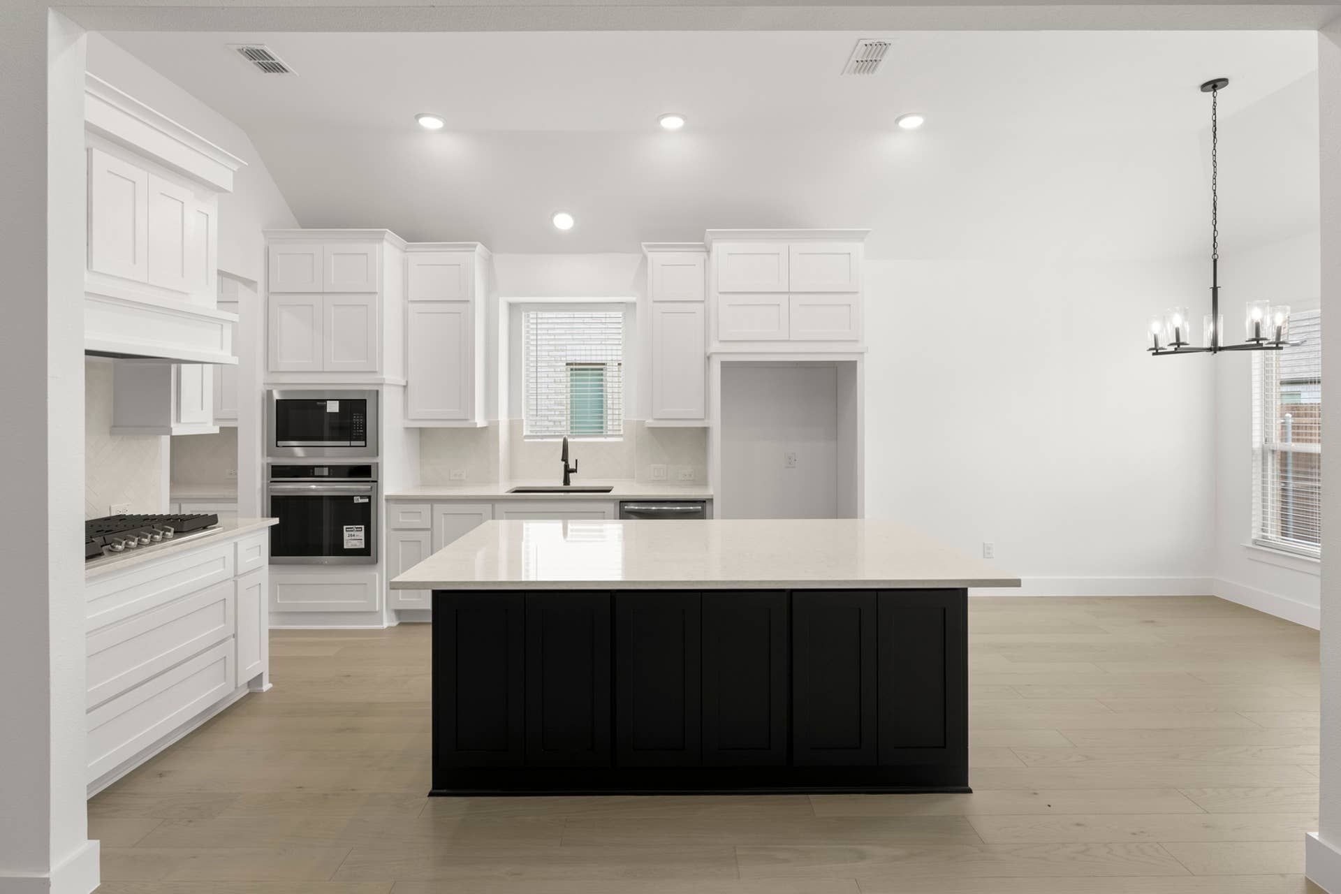Modern kitchen with white cabinetry, large island, and built-in appliances.
